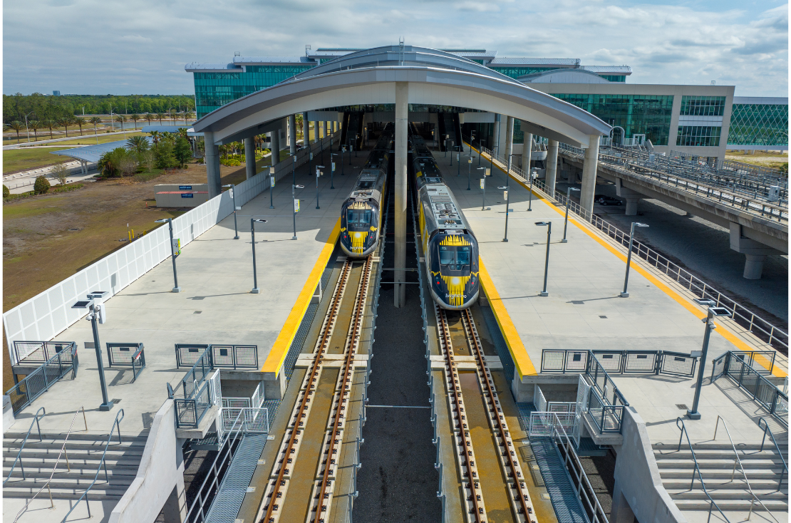 Two Brightline Trains leaving the Orlando Train Station